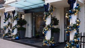 A building facade with columns, a glass entrance, and decorative wreaths. - Guild Hotel Marble Arch (London)