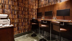 A library with bookshelves, a printer, and bar stools.