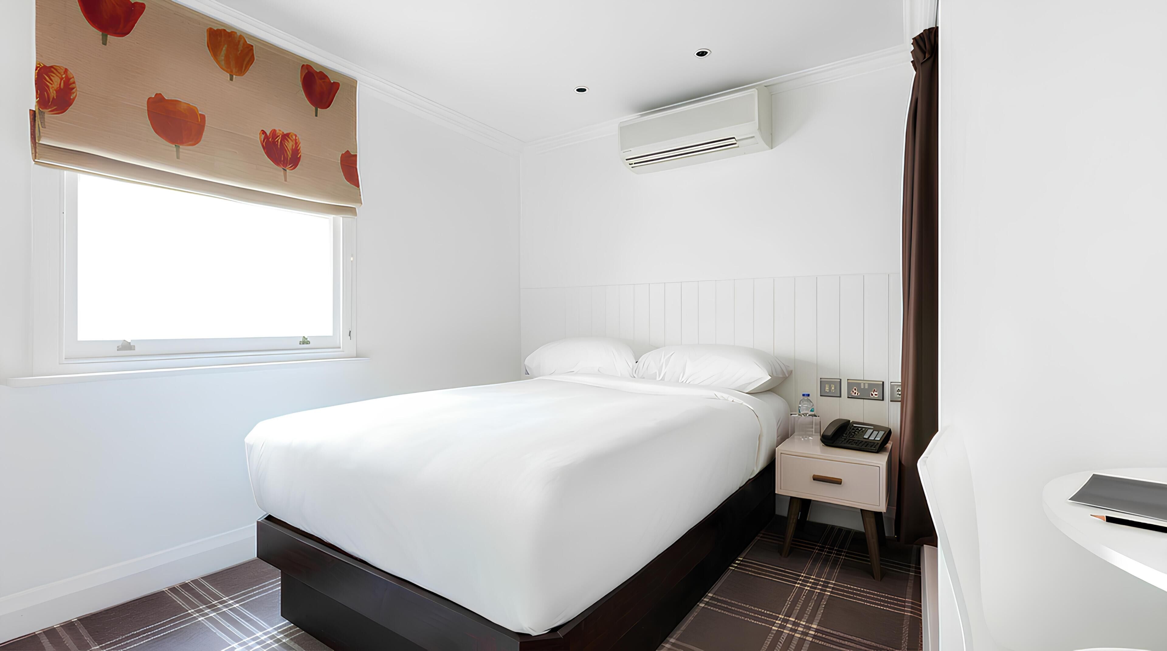 Une chambre d’hôtel moderne avec un grand lit, des tables de chevet, un téléphone sur la table de chevet et une fenêtre donnant sur un beau paysage.