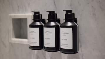 Three black bottles with pump dispensers labeled 'Urban Apothecary' and 'Fig Tree' on a marble wall.