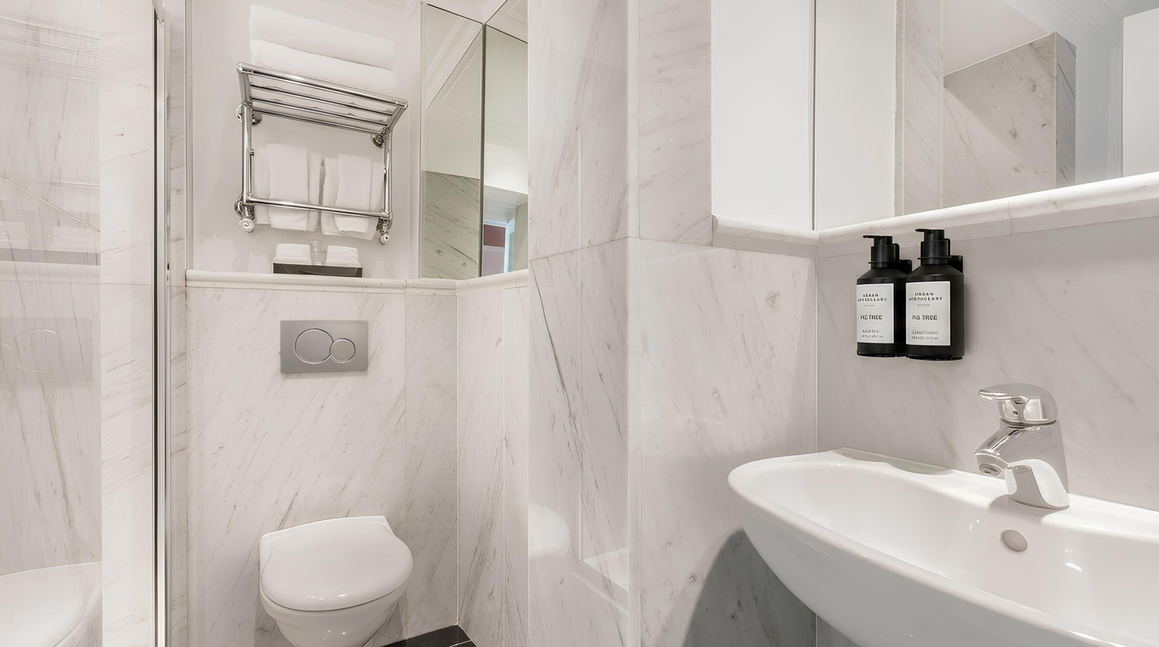 Ein modernes Badezimmer mit Toilette, Waschbecken und Handtuchhalter.