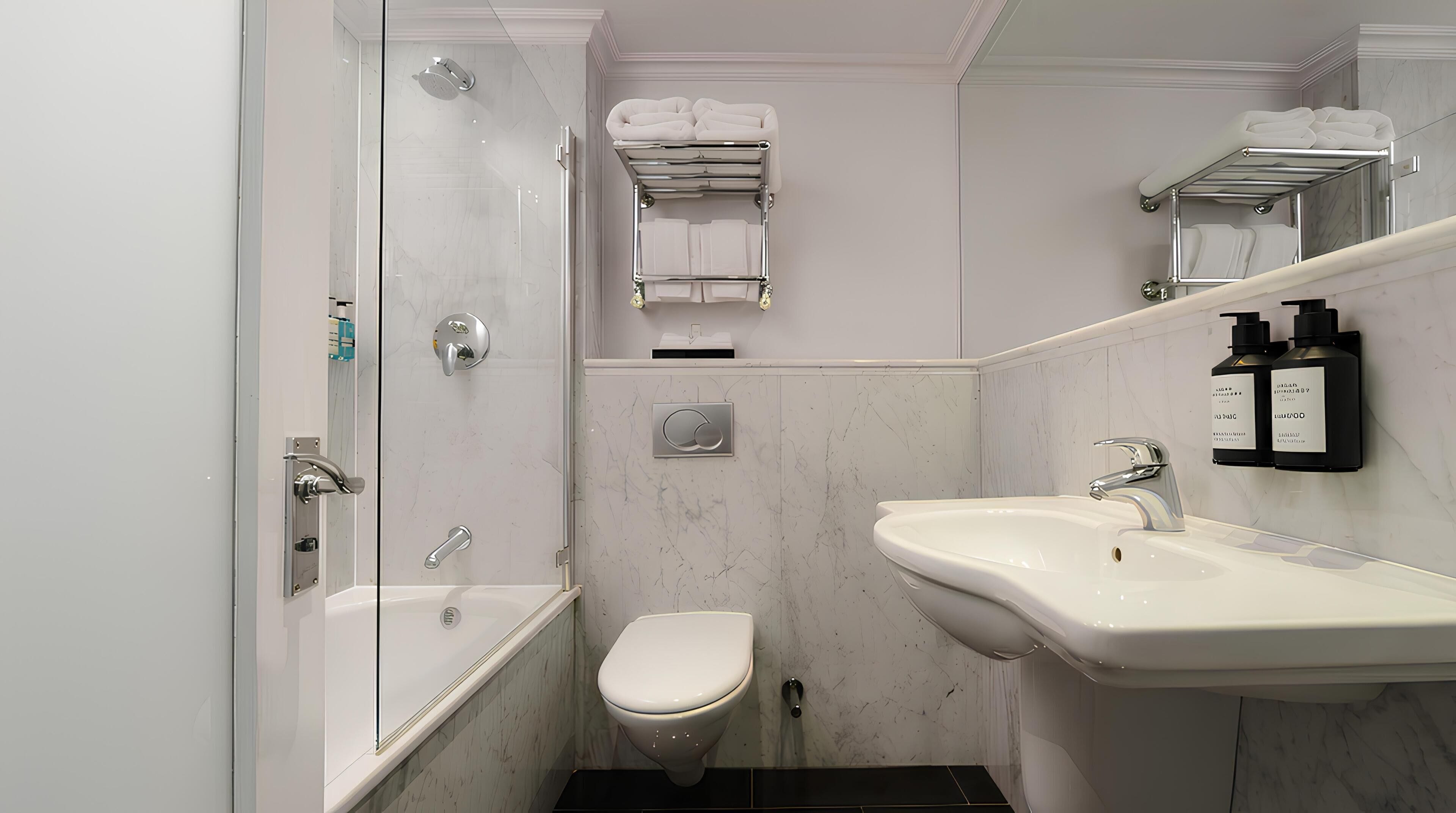 Un baño con ducha, inodoro, lavabo, toallero y espejo.