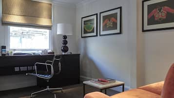 Un espace de bureau moderne comprenant un bureau, une chaise, une lampe, une œuvre d’art encadrée et une fenêtre.