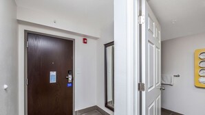 A hallway with a brown door, a white door, and a yellow wall with a towel rack.