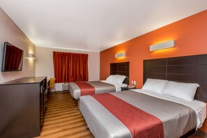 A hotel room with two beds, a desk, and a chair.