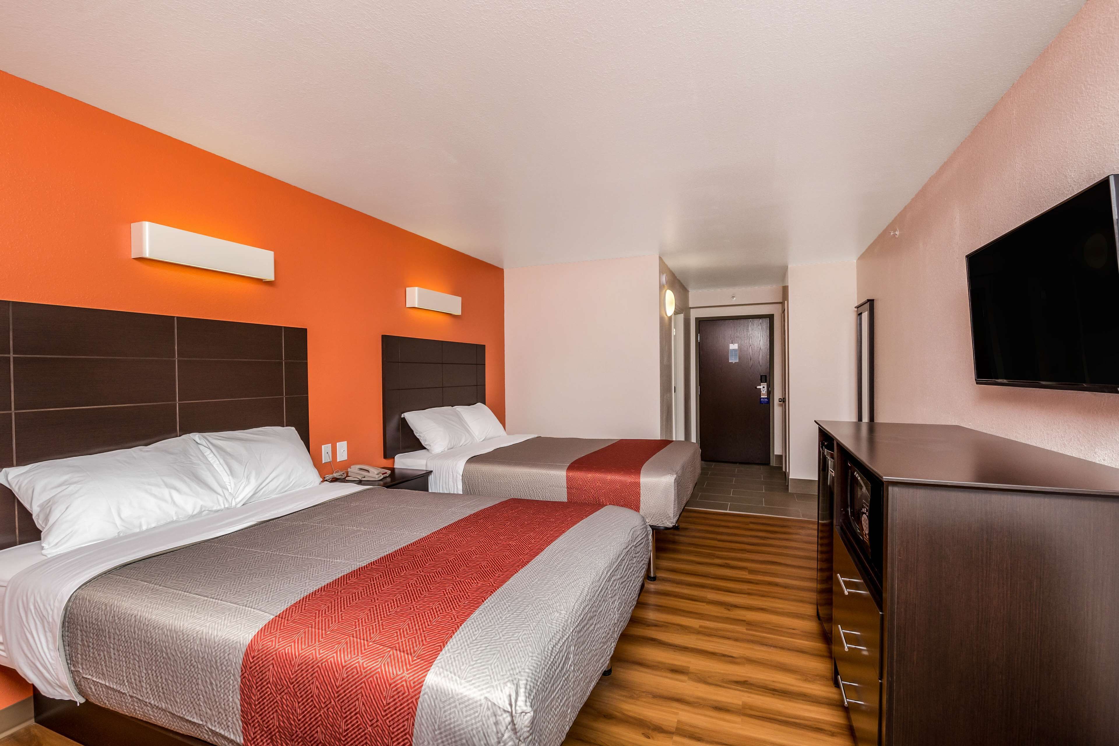 A hotel room with two beds, a TV, a desk, and a wardrobe.