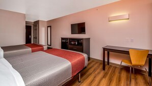 A hotel room with two beds, a desk, a chair, a TV, and a wardrobe.