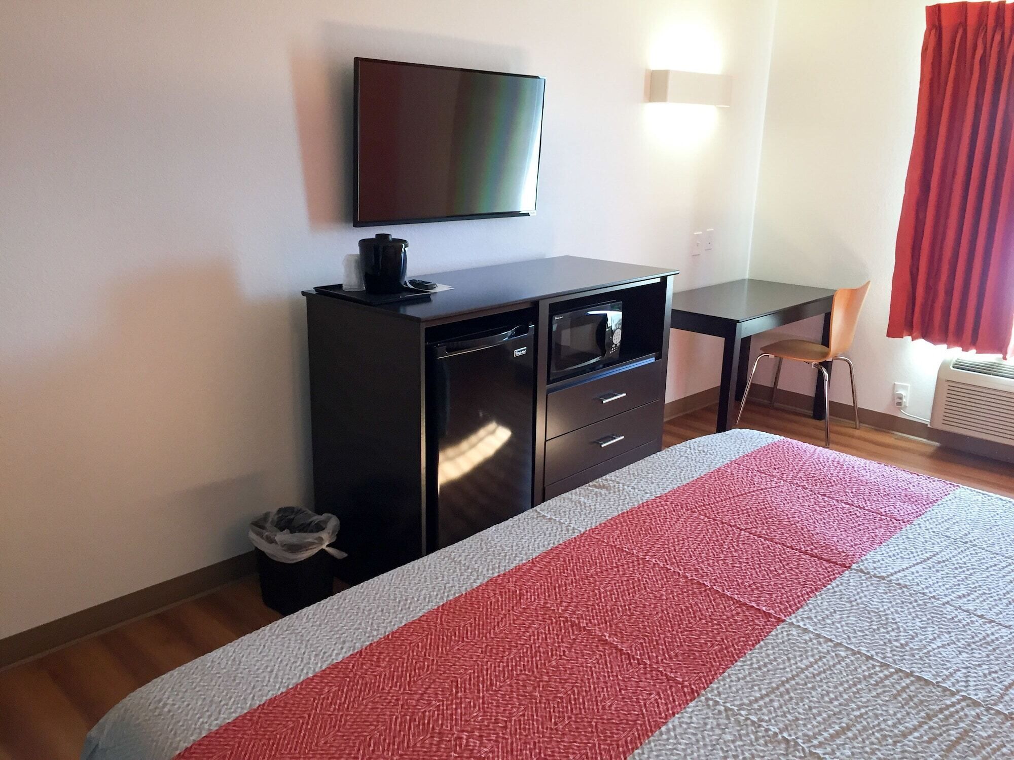 Een hotelkamer met een bed, bureau, televisie en stoel.