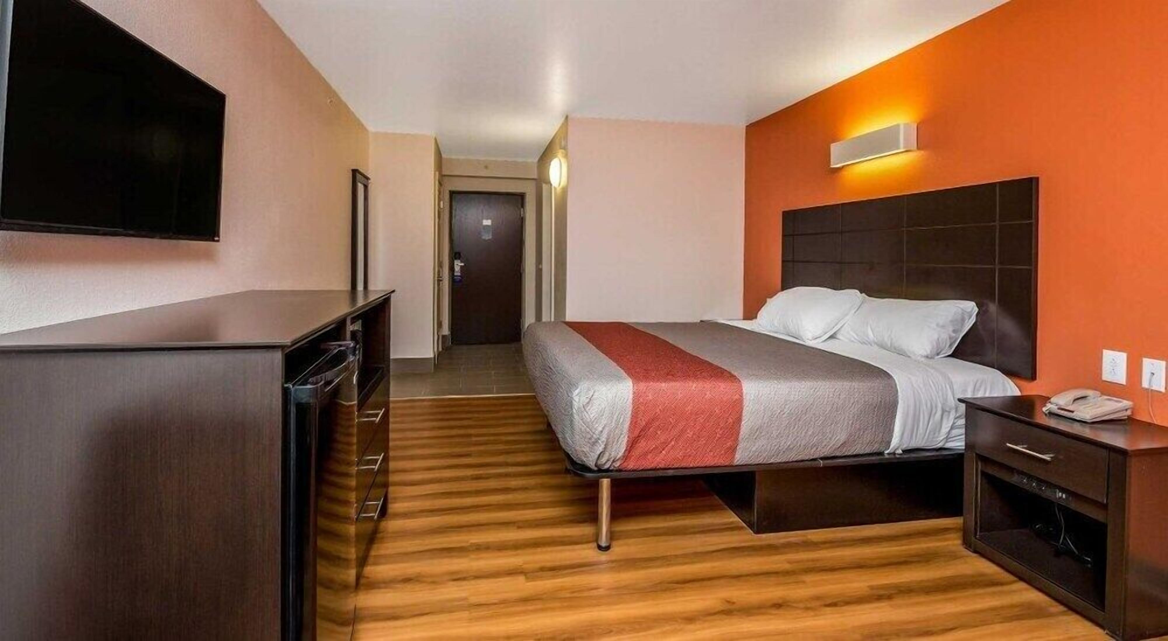 Een hotelkamer met een bed, bureau, televisie en kast.