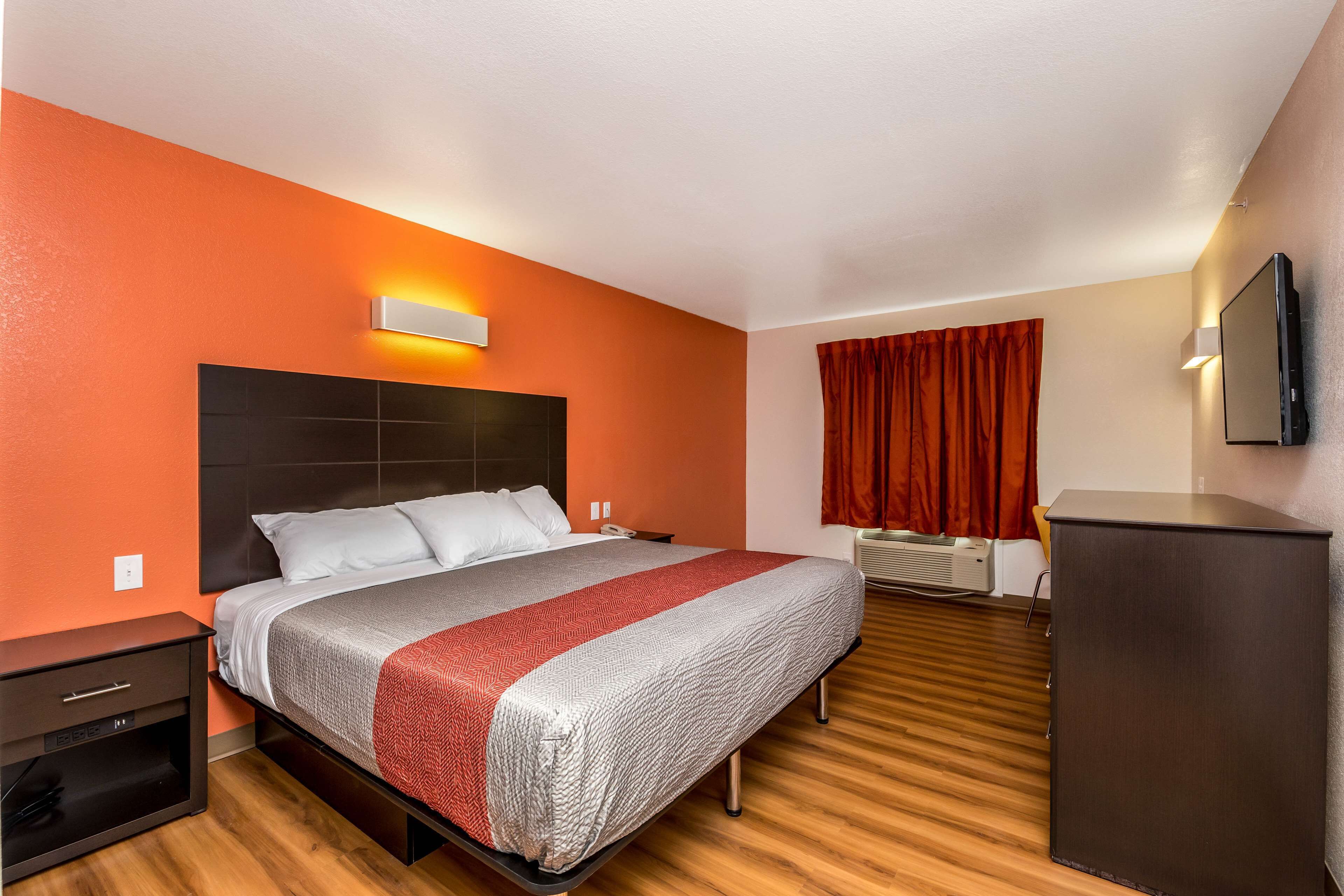 Una habitación de hotel con cama, escritorio, televisión y armario.