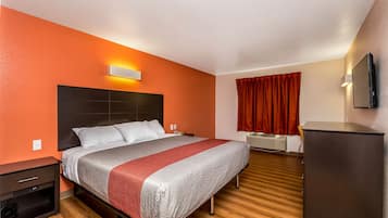 Una habitación de hotel con cama, escritorio, televisión y armario.