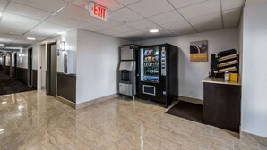 A hotel lobby with a vending machine, a coffee machine, and an exit sign.