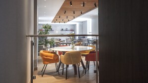 A modern dining area with a round table and chairs, a glass partition, and a wooden ceiling.