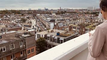Un balcón con vistas a una zona urbana densamente poblada, con varios edificios y un cielo nublado.