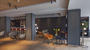 A modern interior with wooden flooring, a bar area, and seating arrangements. - ibis Styles Den Haag Scheveningen (The Hague)
