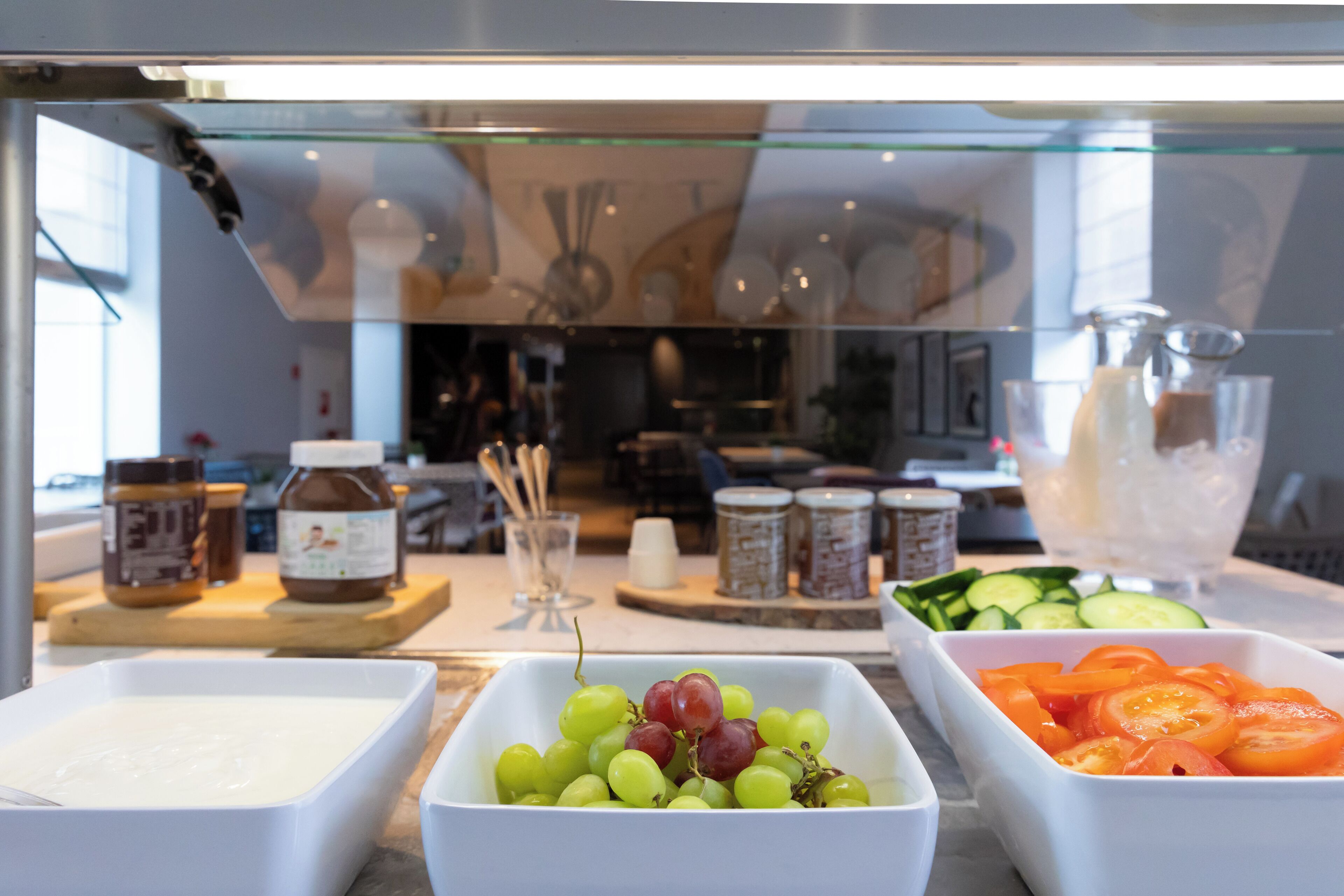 Un bufé con diversos alimentos, incluyendo uvas, tomates y un plato cremoso.