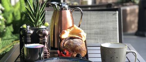 Una mesa de desayuno con un plato de comida, una taza de café y un mantel enrollado.