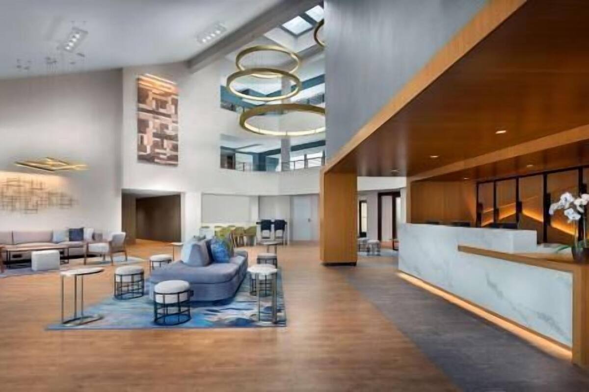 A spacious lobby with a reception desk, seating area, and a high ceiling with circular light fixtures.
