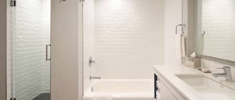 Un baño moderno con cabina de ducha de vidrio, una bañera blanca y un espejo grande sobre el lavamanos.