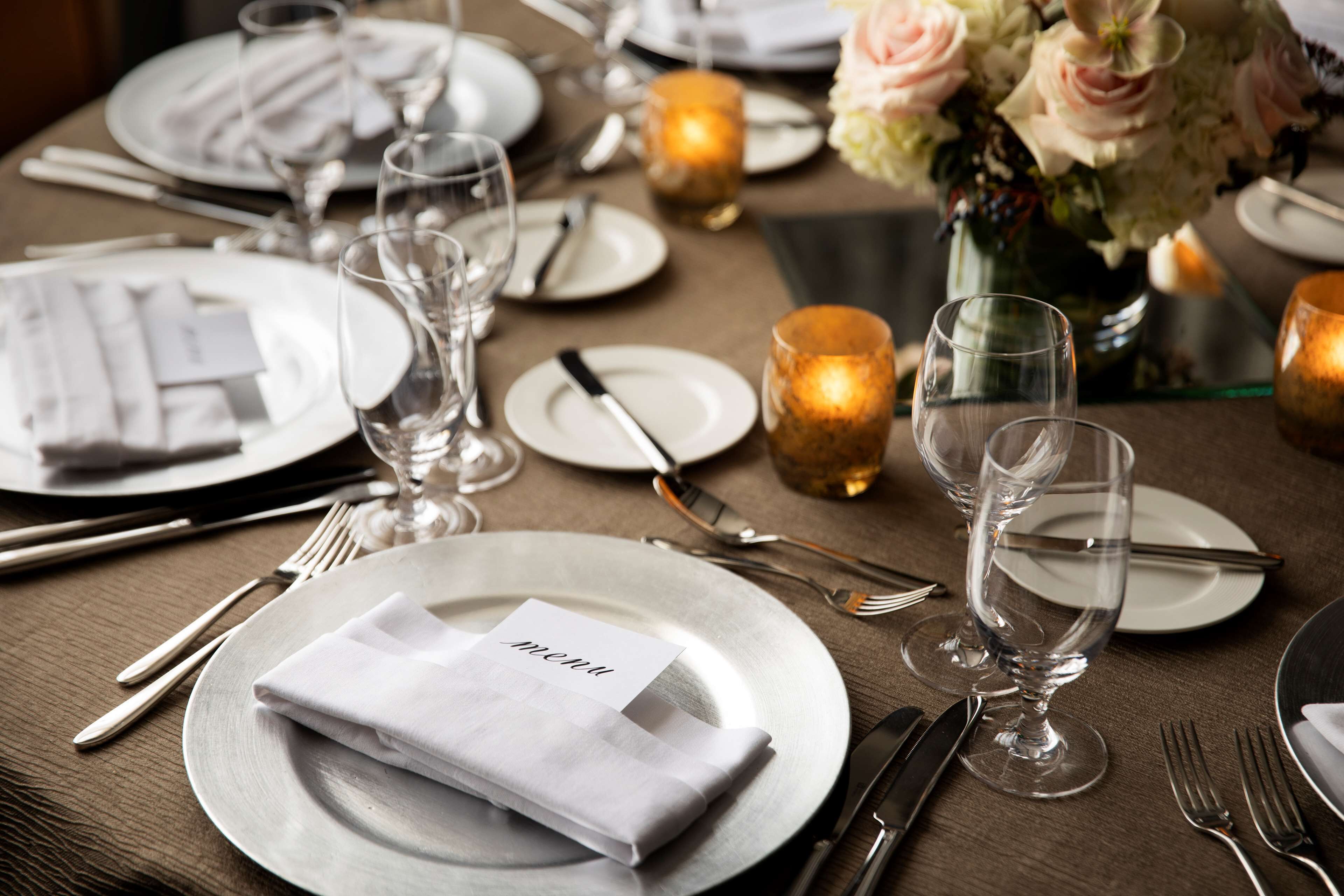 A table set for a formal dinner with plates, cutlery, glasses, and candles.