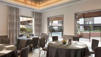 A conference room with round tables, chairs, and a view of a swimming pool.