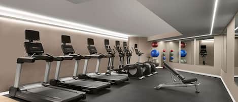 A gym with multiple treadmills, exercise balls, and a rowing machine.