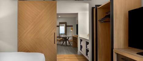 A hotel room with a bed, a desk, a chair, a TV, and a wardrobe.