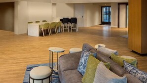 Un vestíbulo amplio con techo alto, una zona de estar central con sofá y sillones, y una escalera que conduce a un nivel superior.