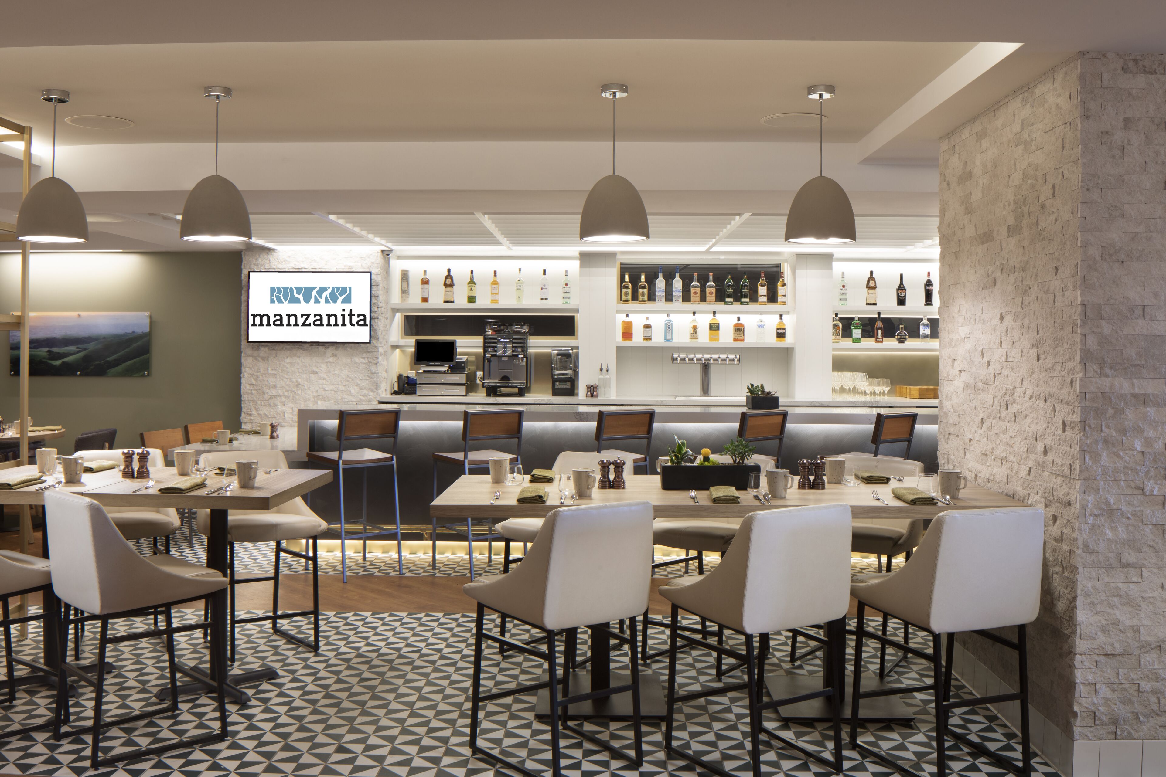Un restaurant moderne doté d’un bar, de plusieurs espaces pour s’asseoir et d’un large choix de boissons exposées.