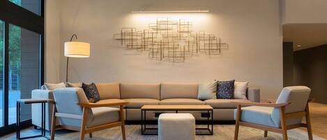 A modern living room with a sectional sofa, two armchairs, a coffee table, and a floor lamp.