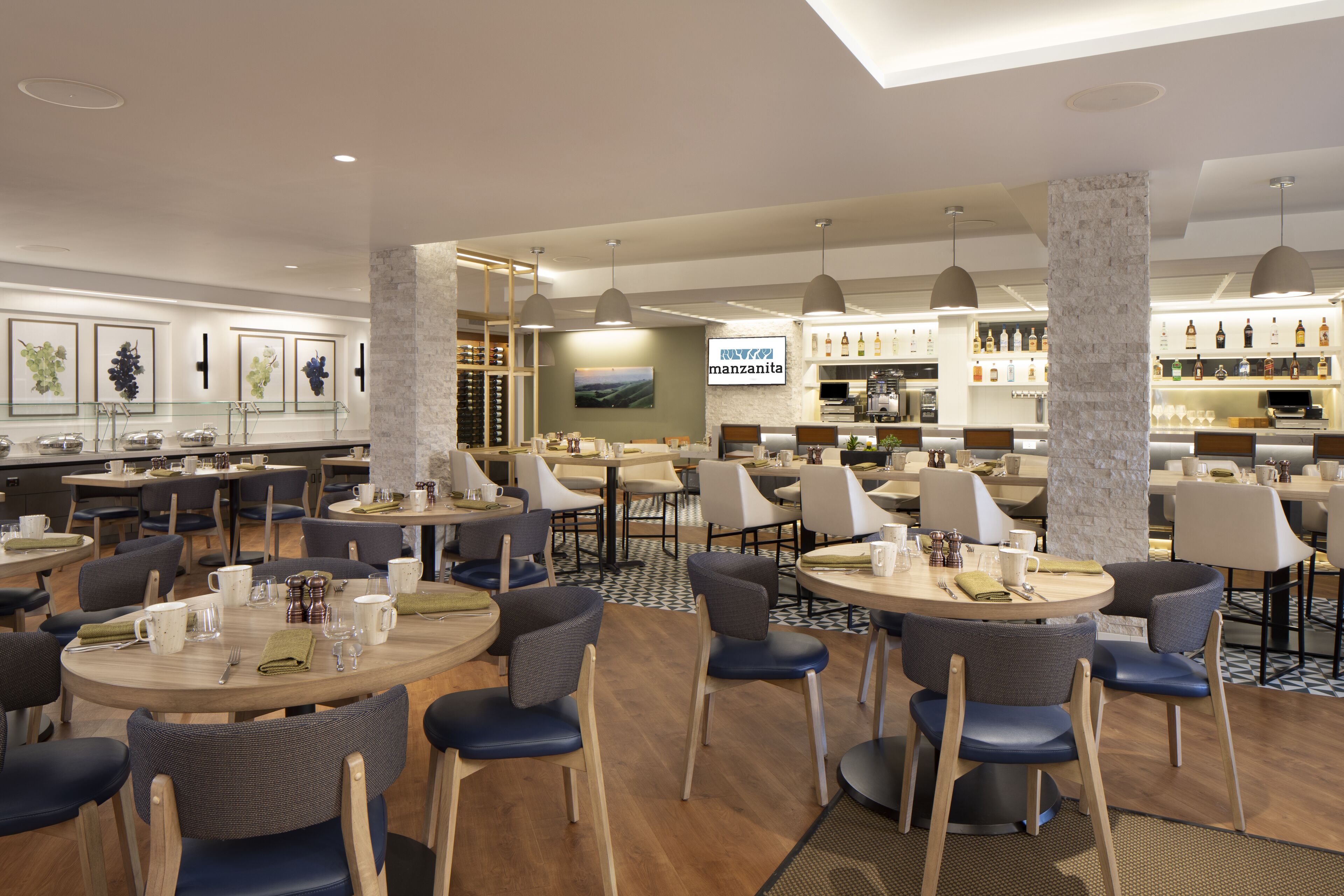 Een modern restaurant met ronde tafels en stoelen, een bar en uitzicht op de stad.