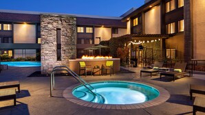 Un hotel con piscina, zona de estar al aire libre y una chimenea.