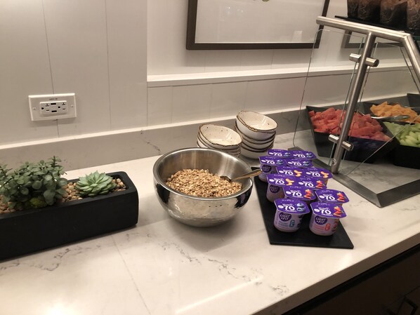 A buffet setup with various food items, including bowls of granola and fresh fruits, and containers of yogurt. - Sonesta Silicon Valley (Milpitas)