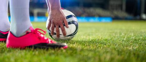 Primer plano del pie de un futbolista tocando un balón en un campo de césped.