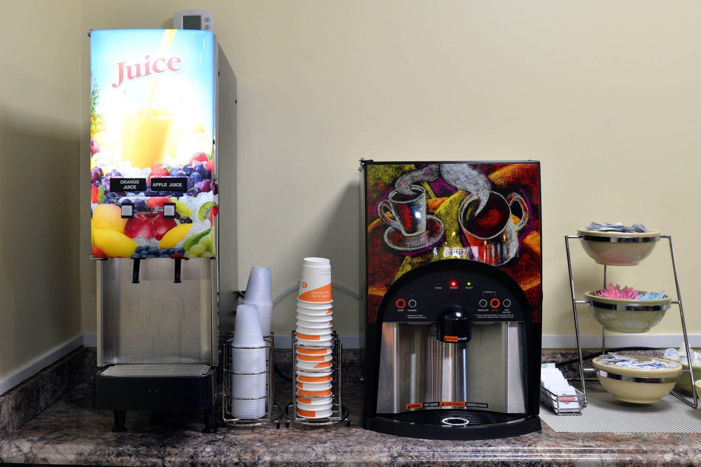 A juice dispenser, a coffee machine, and a paper towel dispenser on a counter.