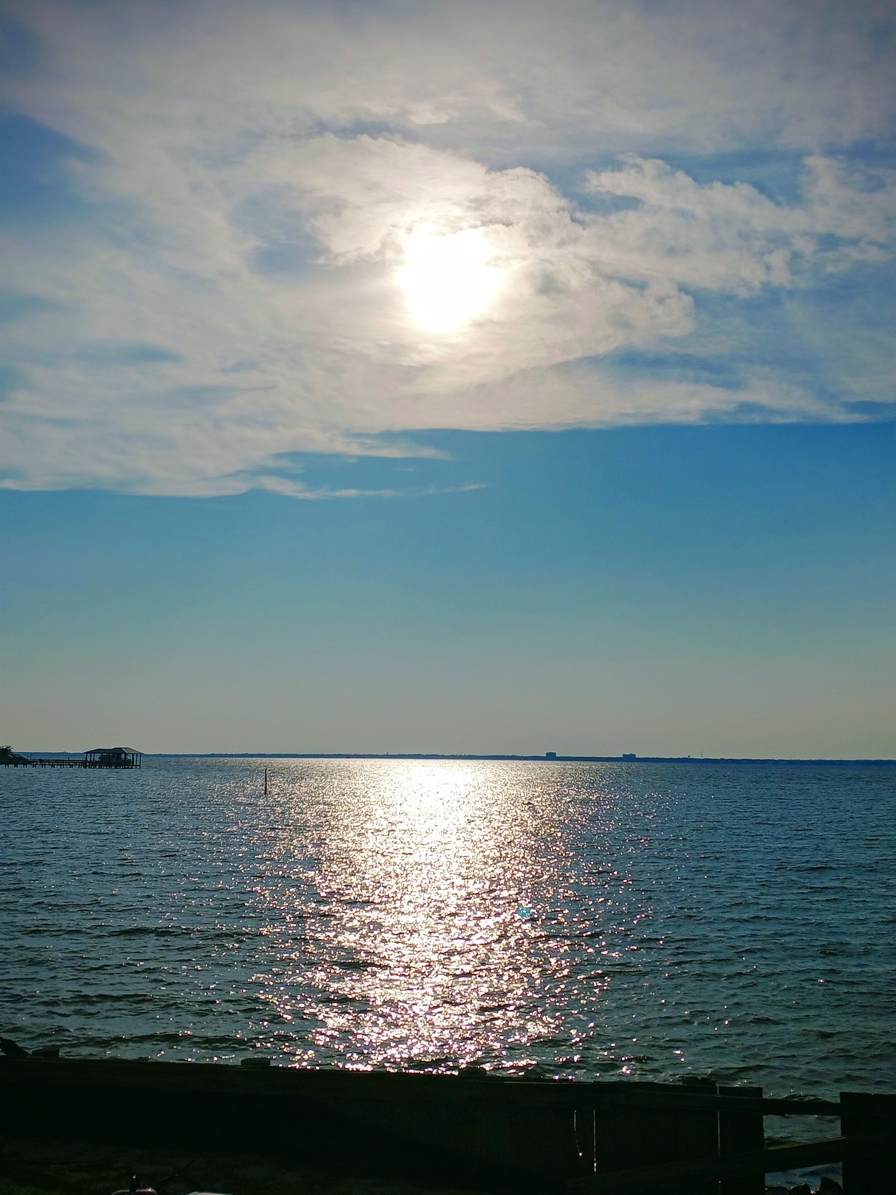 A calm body of water reflecting sunlight with a clear sky above.