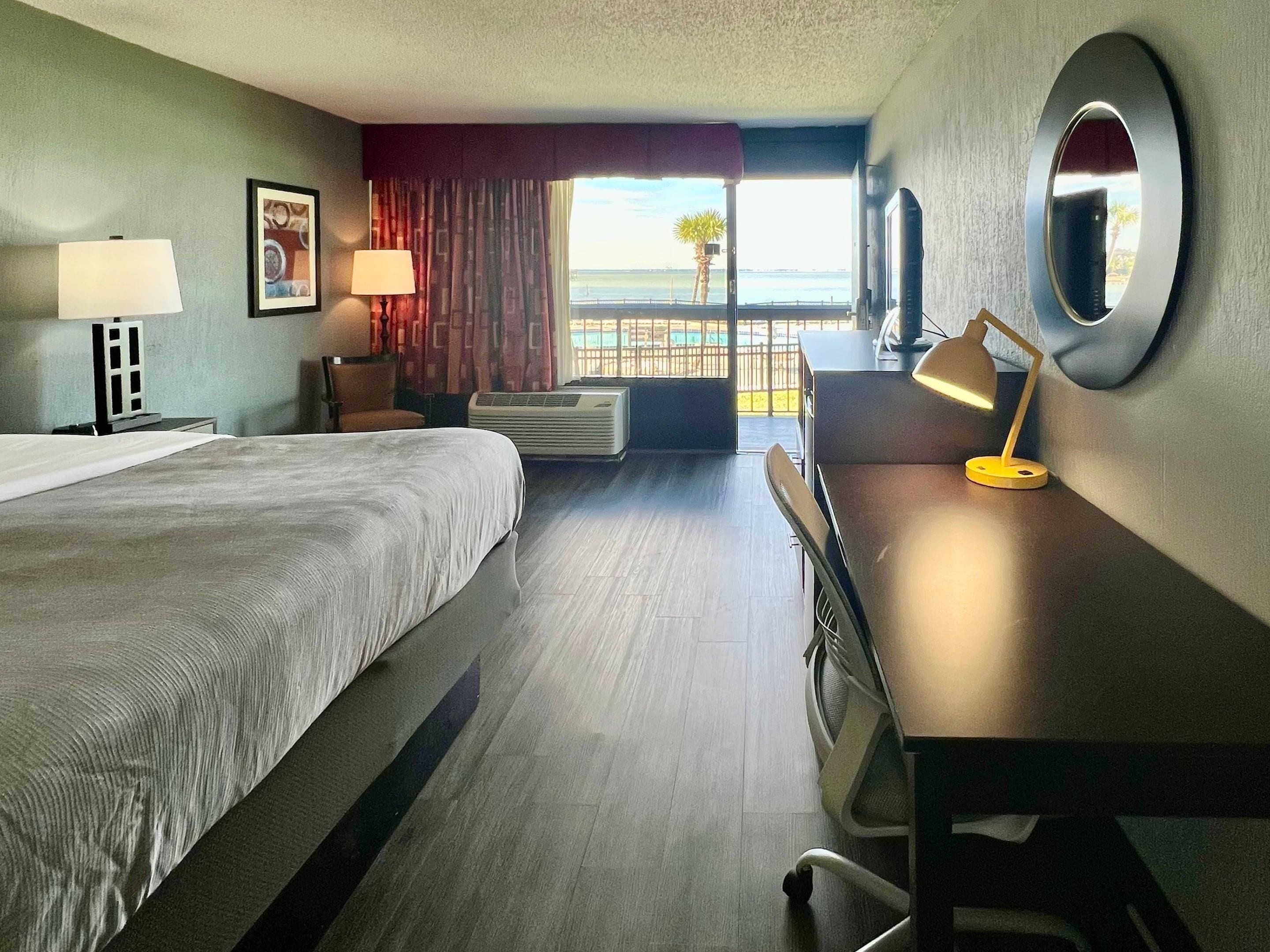 Une chambre d’hôtel équipée d’un lit, d’un bureau, d’une chaise, d’une lampe, d’un climatiseur et offrant une vue sur la mer.