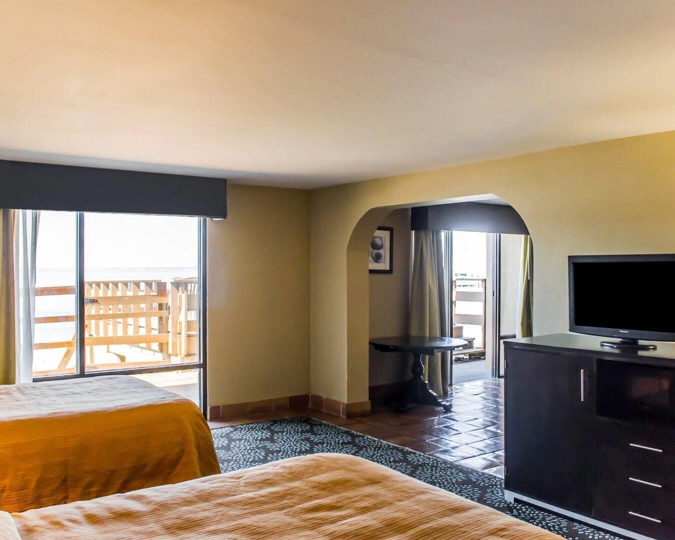 Habitación de hotel con cama, televisor, escritorio y vistas al exterior.