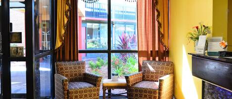 A room with two patterned chairs, a small table, and a window with curtains.