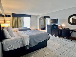 Une chambre d’hôtel équipée d’un lit, d’un bureau, d’une chaise, d’une télévision et d’un miroir.