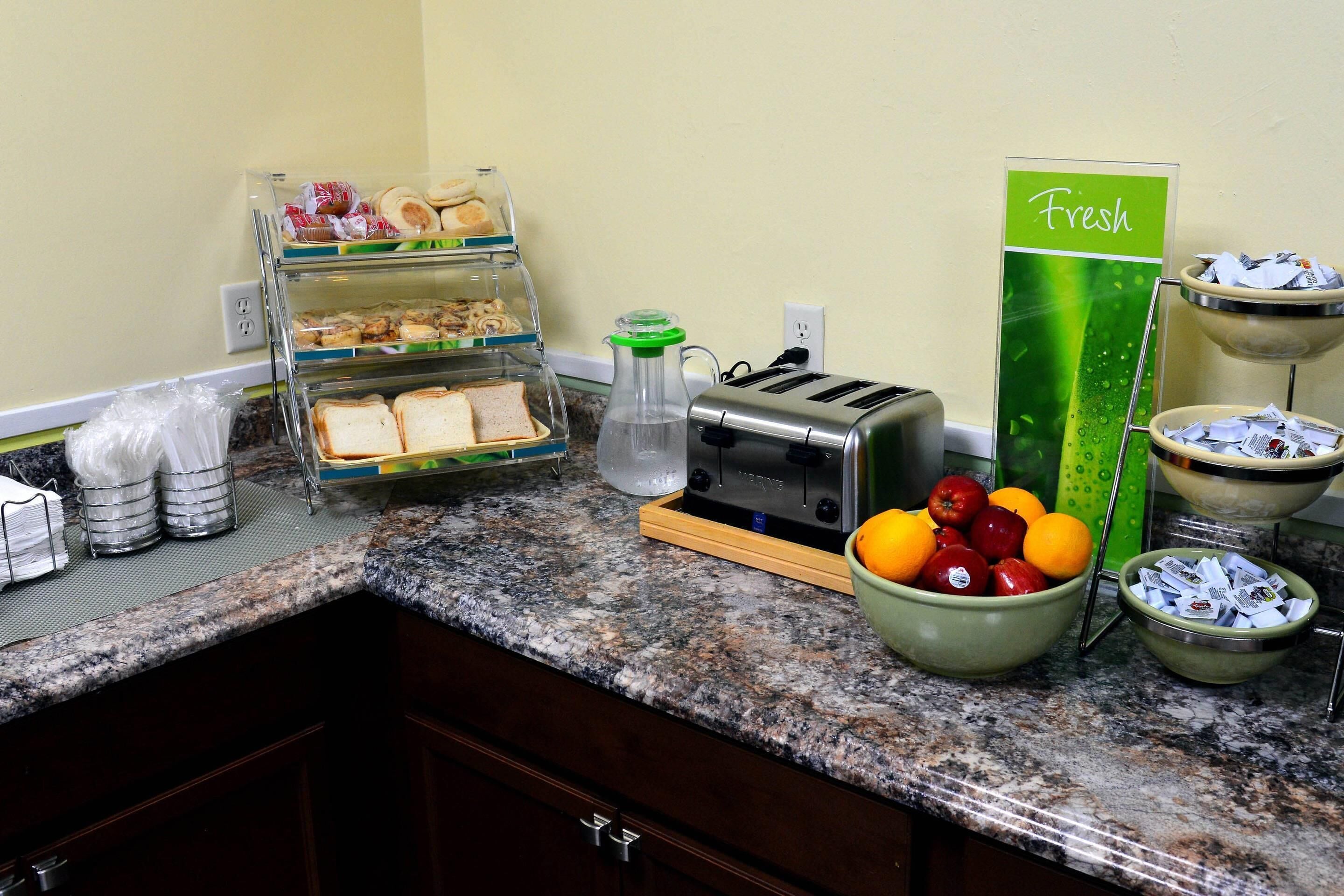 Un bufé de desayuno con diversos alimentos, un tostador y un letrero que dice 'Fresh'.