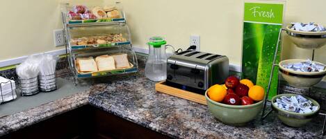 Un buffet de petit-déjeuner proposant divers aliments, un grille-pain et une pancarte indiquant « produits frais ».
