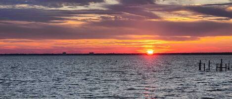 A sunset over a body of water with a distant shoreline and a few buildings.