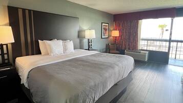 Habitación de hotel con una cama grande, dos mesitas de noche con lámparas, una ventana con cortinas y vistas al exterior.