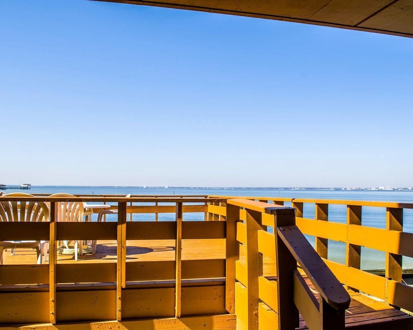 Una terraza de madera con barandilla que da a un cuerpo de agua.