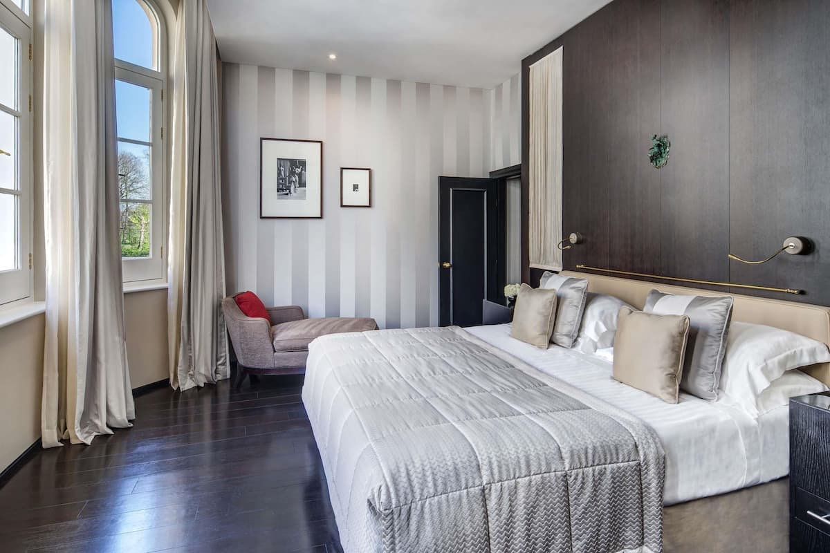 A modern bedroom with a large bed, a chair, and a wardrobe.