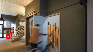 A modern interior with a staircase, a glass door with a wooden panel, and a patterned carpet. - ibis Epernay Centre Ville (Epernay)