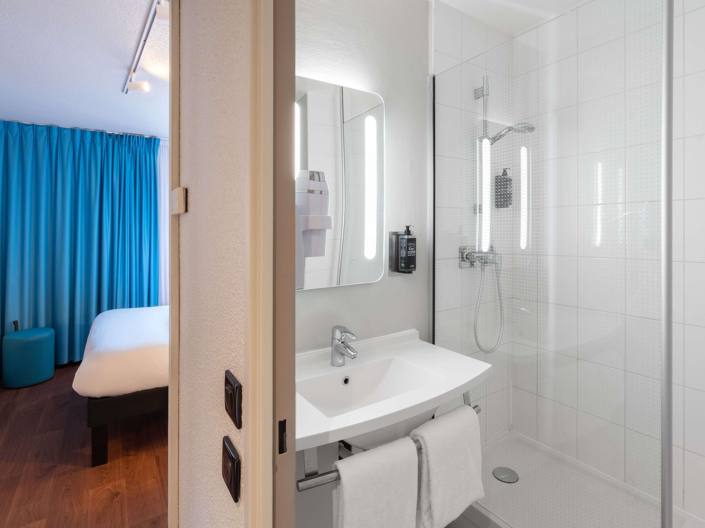 Un baño moderno con ducha, lavamanos y espejo.