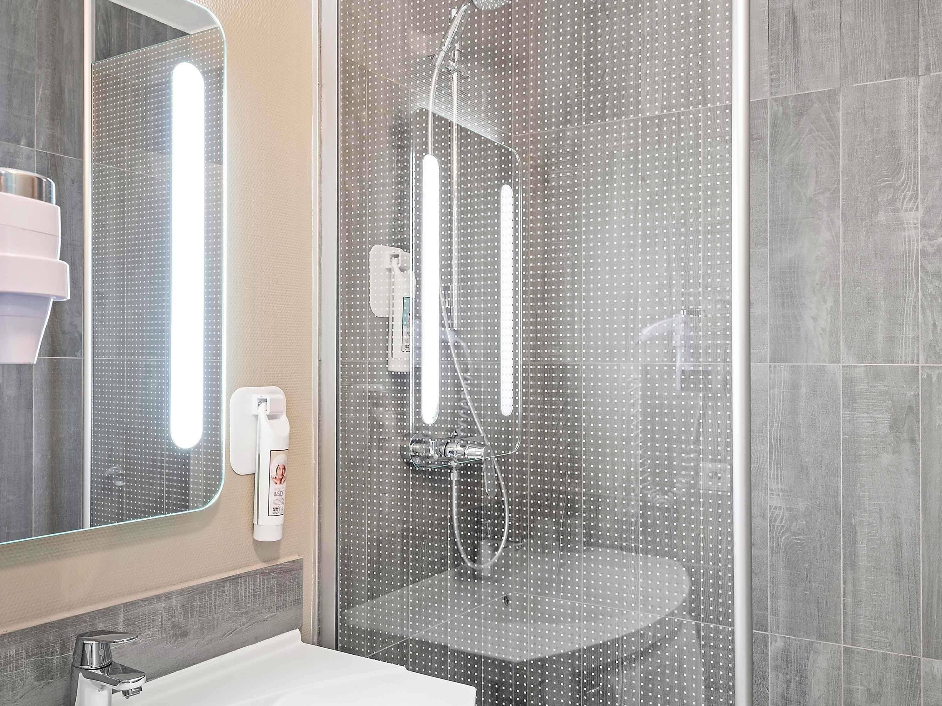 A modern bathroom with a glass-enclosed shower, a sink, and a mirror.