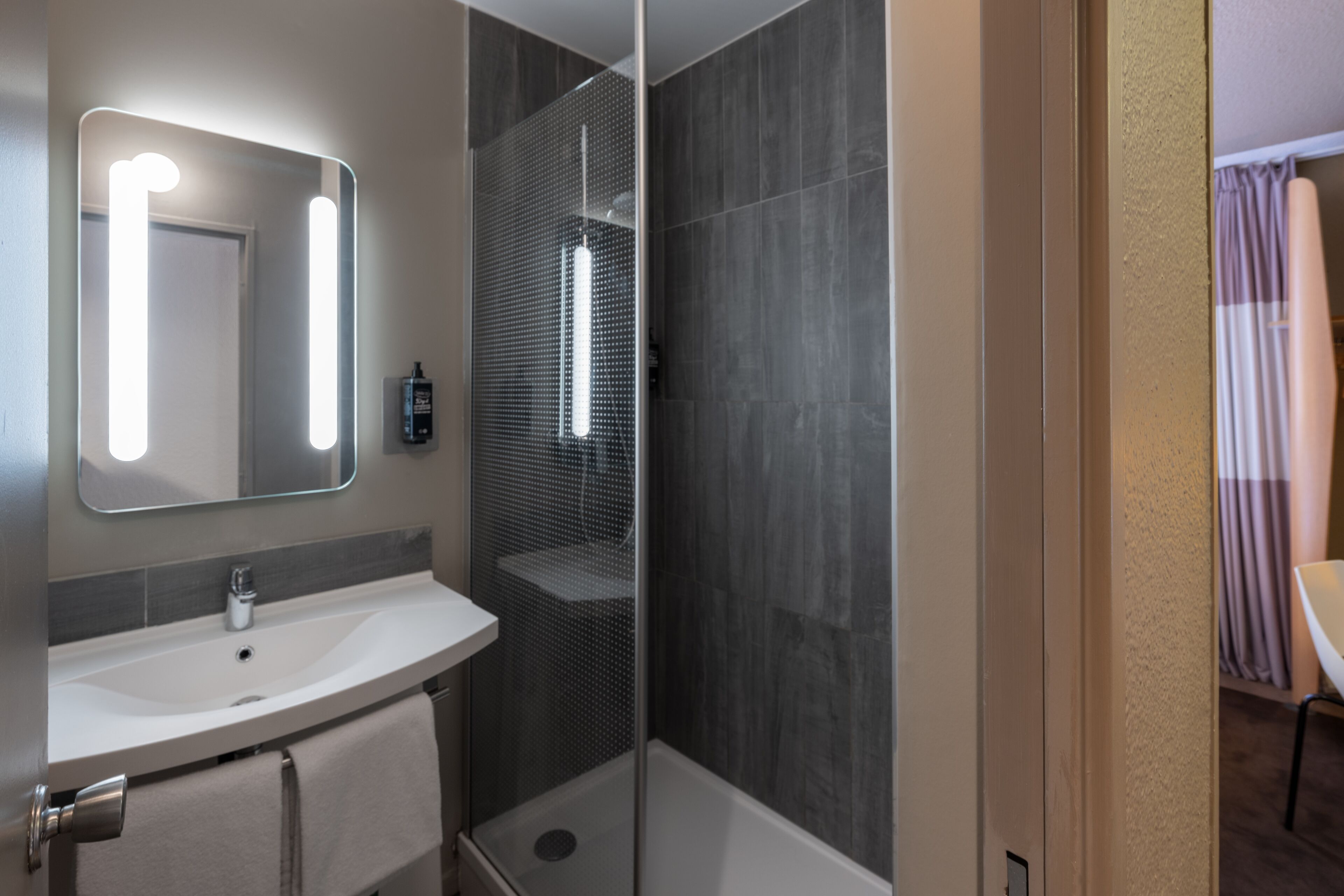 Une salle de bain moderne avec un meuble-lavabo, un miroir et une cabine de douche.